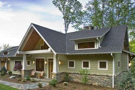 A sage green house with stone base and white trim