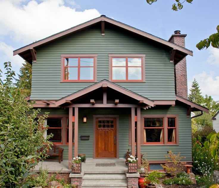 A sage green house with brown trim and windows and wooden door 