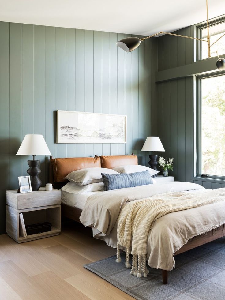 A shiplaps green wall and white celling and glass windows and wooden floor and rug on it 