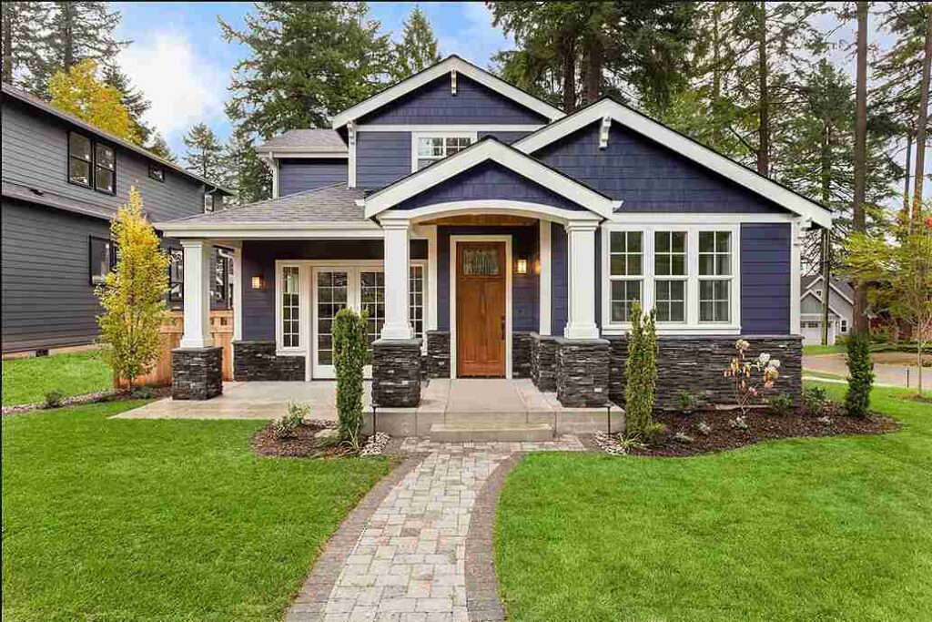 A blue house with stone base pillar and garden outside of the house 