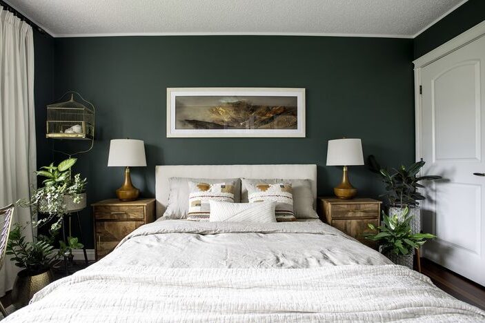 A green bedroom with white bedding and wooden nightstand 