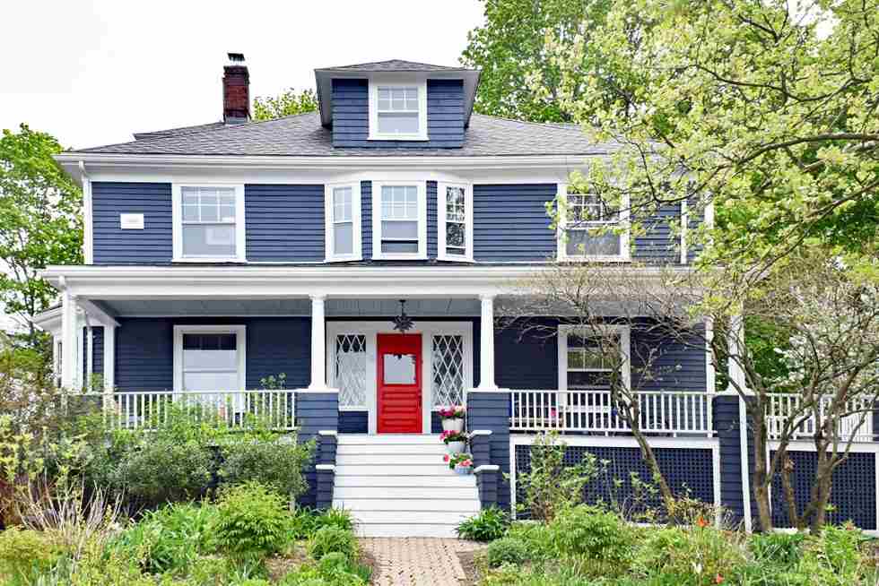 A blue house with white stair and red door and window 