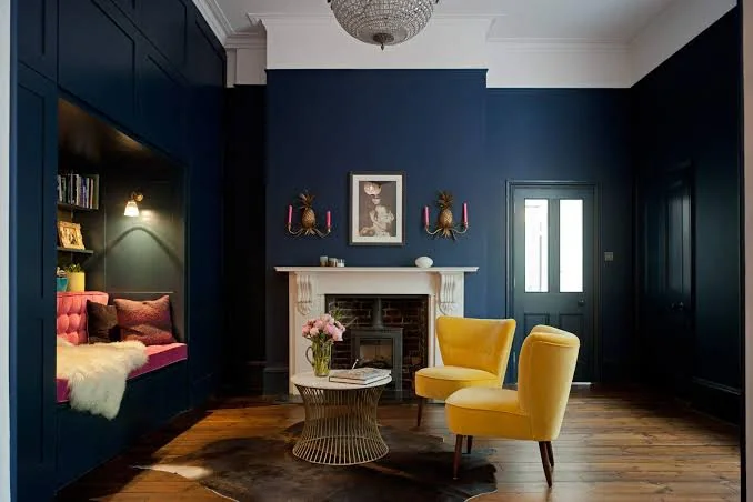 A navy blue living with wooden floor and yellow chairs