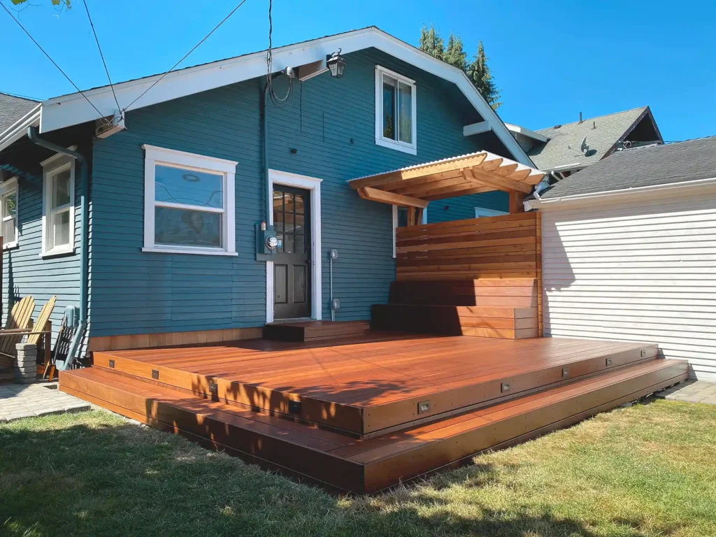A blue house with wooden porch and garden outside of the house 