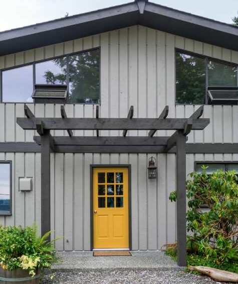 A grey house with black trim and yellow door