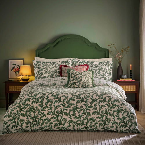 A sage green bedroom with textiles and lamp on the side table 