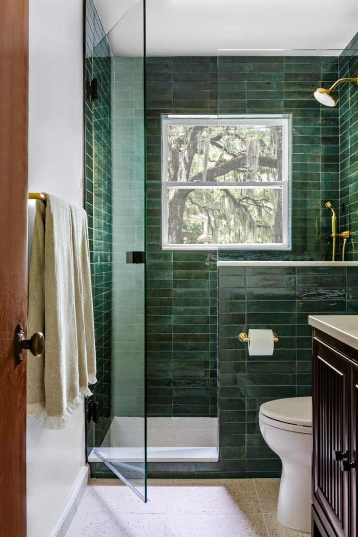 A green bathroom with subway tiles and glass shower door