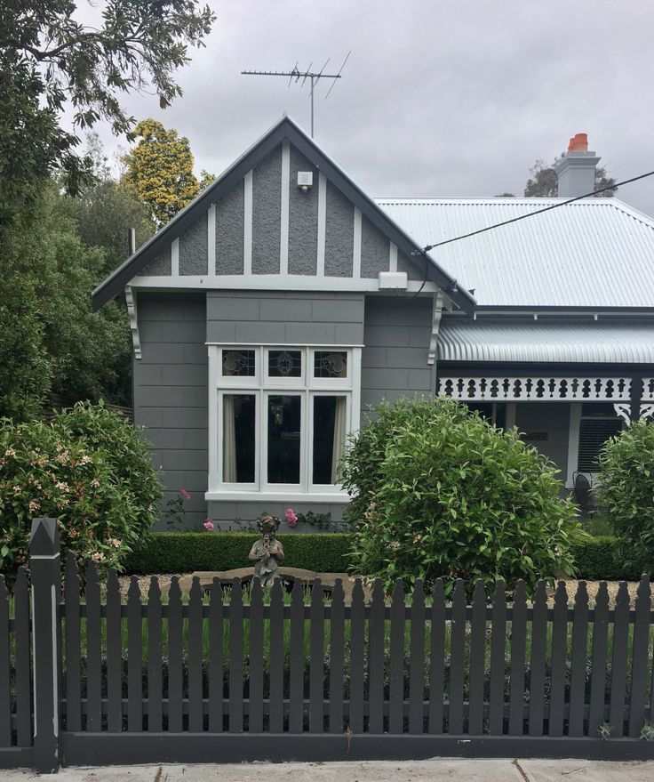 A light grey house with black fencing around the house