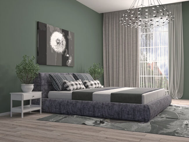 A green and grey bedroom with frames on the wall and rug on the floor 