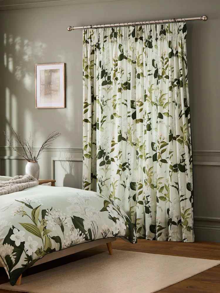 A botanical print curtains in bedroom with wooden floor and rug on it 
