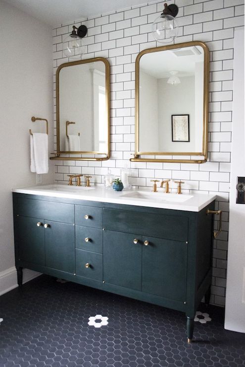 A green bathroom with green vanity and brass accents