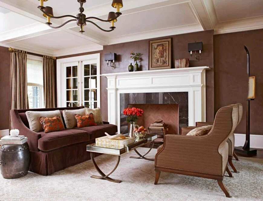 A brown living room with white trim fireplace and windows with curtains 