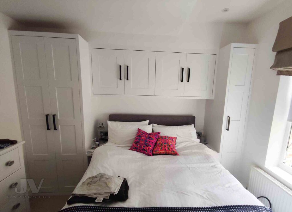 A bedroom with built wardrobe and bed with pillow and cushion