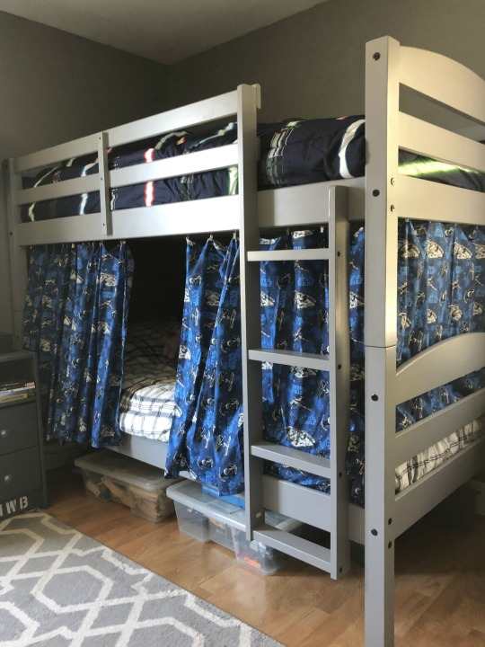 A bedroom with curtain and loft bed bed and wooden floor