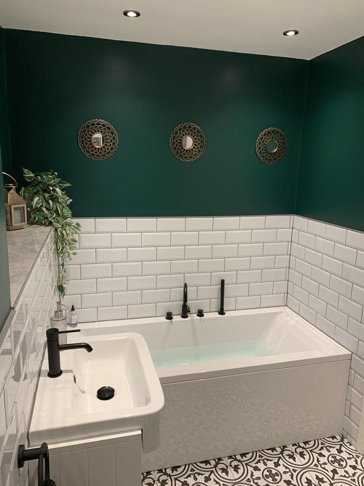 A white and and green bathroom with white bathtub with black fixture