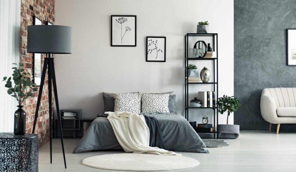 A bedroom with wall art on the wall and brick wall and lamp and shelves 
