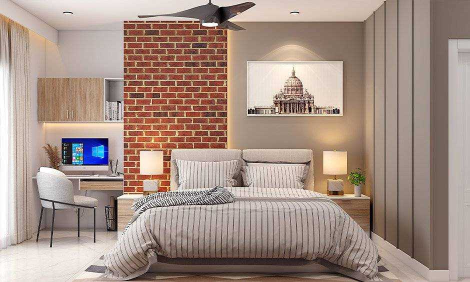 A bedroom with exposed wall and study table on the side and  lamp on the nightstand 