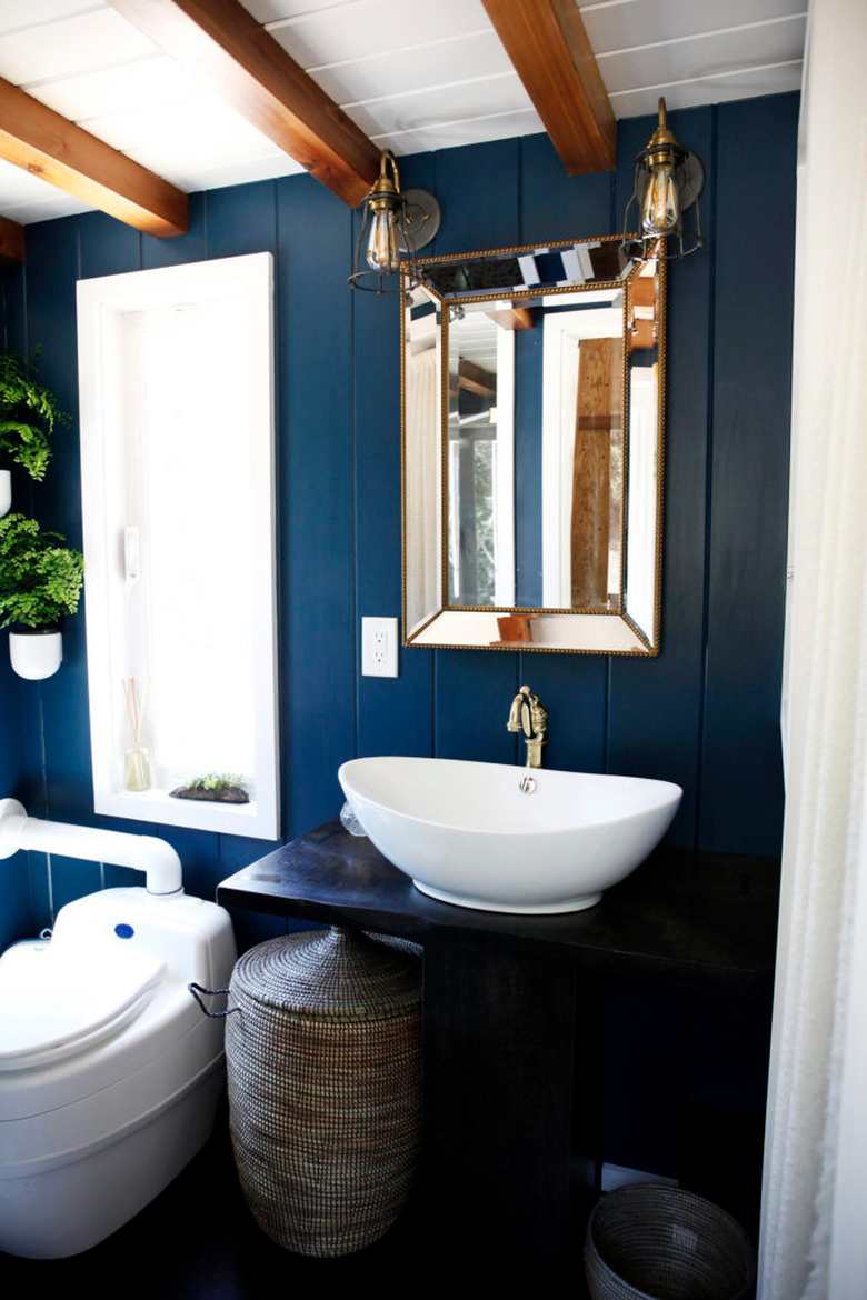 A navy blue bathroom with mirror on the wall and white floating sink