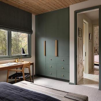 A forest green wardrobe in bedroom with wooden floor and windows 