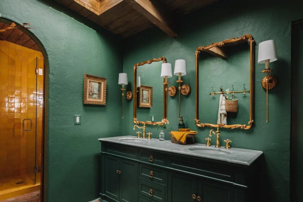 A green bathroom with gold frame mirror on the bathroom with green vanity