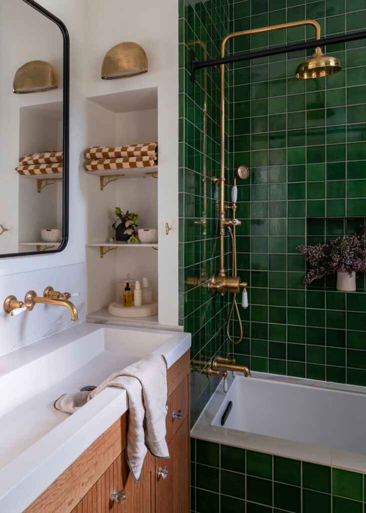 A green bathroom with gold accents and wooden vanity