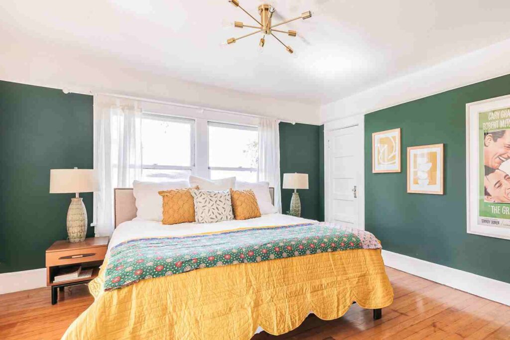 A green bedroom with white trim and wooden floor