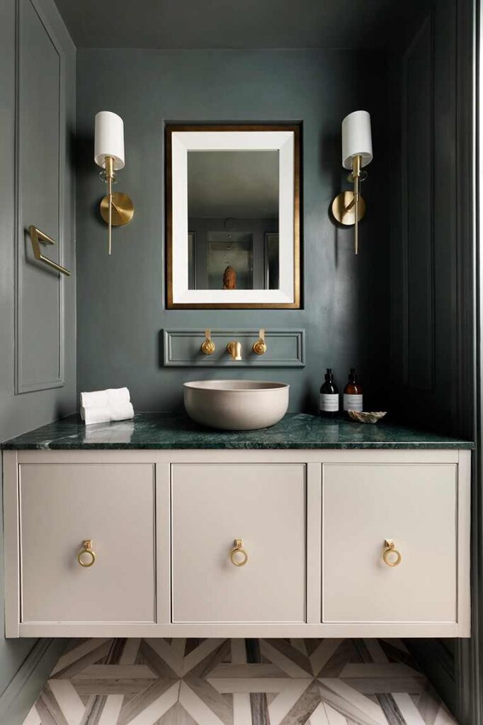 A marble green countertop and white vanity and gold accents