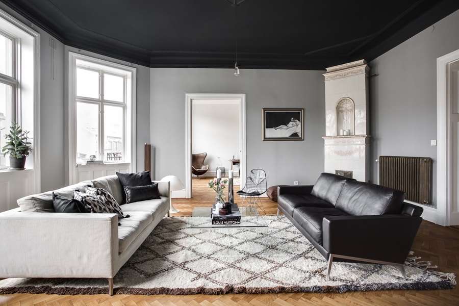 A black celling with grey walls and wooden floor and rug on it 