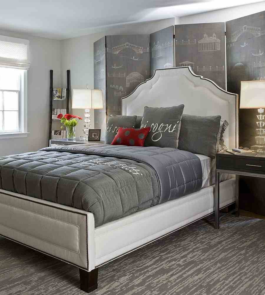 A grey bedroom with white bedding and windows and side table with lamp on it
