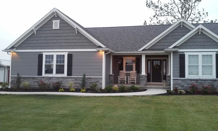 A grey house with white trim and black shutter and garden outside of the house 