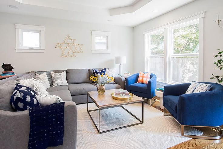A grey sofa with blue chairs and table and wooden floor