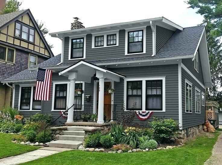 A grey house with white trim and gutter and black framed windows 