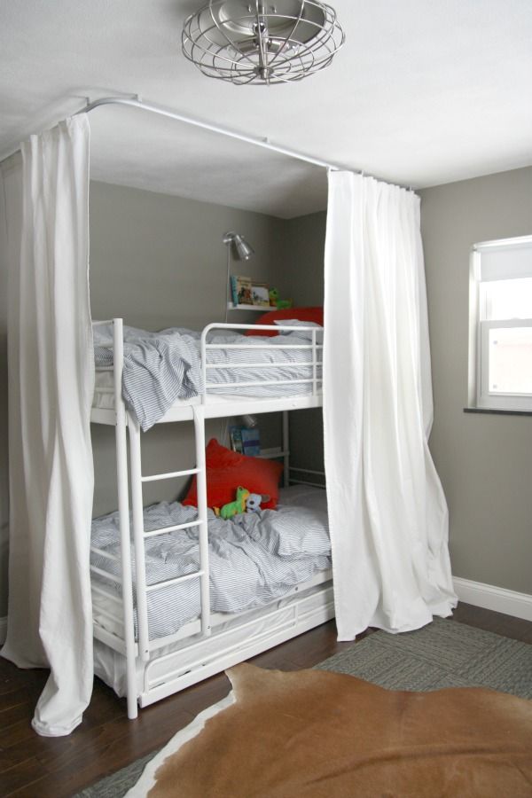 A loft bed with white curtain and windows and wooden floor 