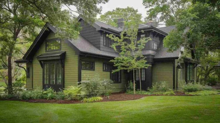 A dark green house with black trim and garden outside of the house