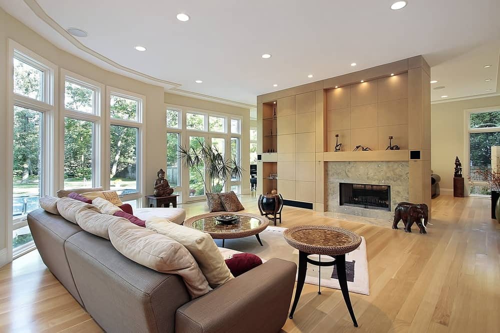 A living room with larges windows and wooden wall with shelves and floor 