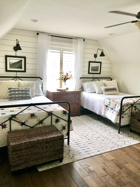 A small bedroom with lights on the wall and windows and curtains