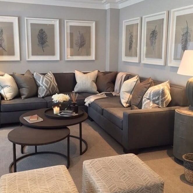 A light grey living room with brown sofa with cushion and white frames on the wall 