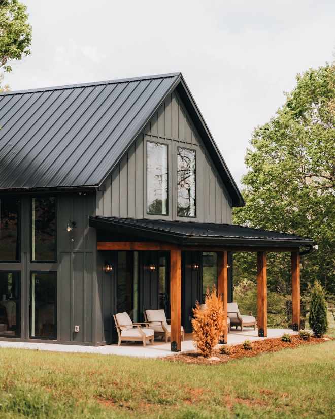 A grey house with board and batten and black trim and roof and garden outside of the house