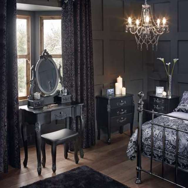 A vanity and dresser in bedroom with wooden floor and iron bed
