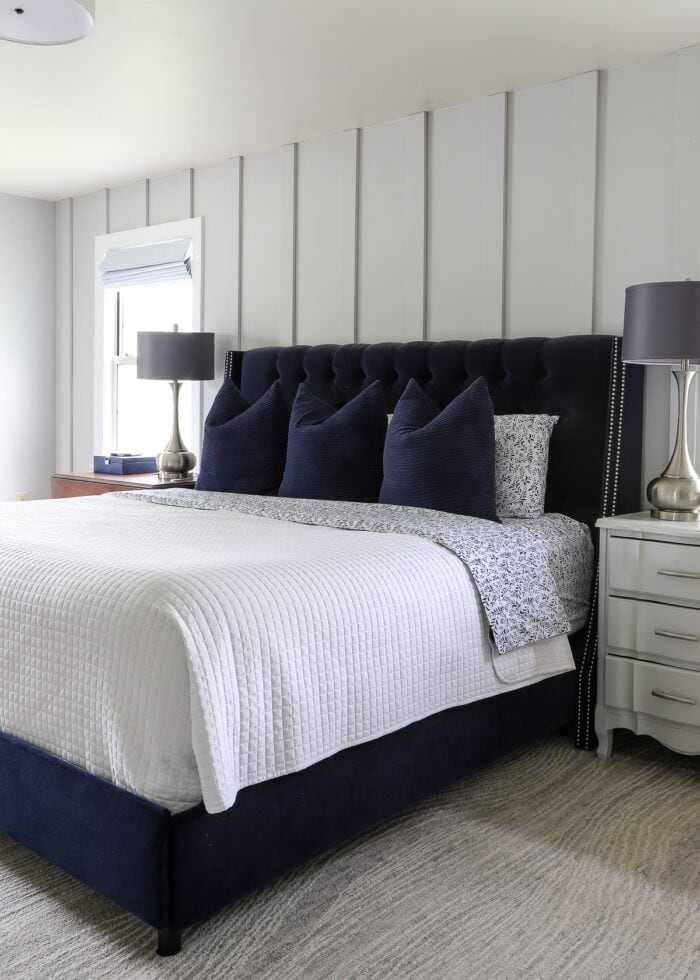 A navy bedding in grey bedroom with wooden floor and lamp on the nightstand 