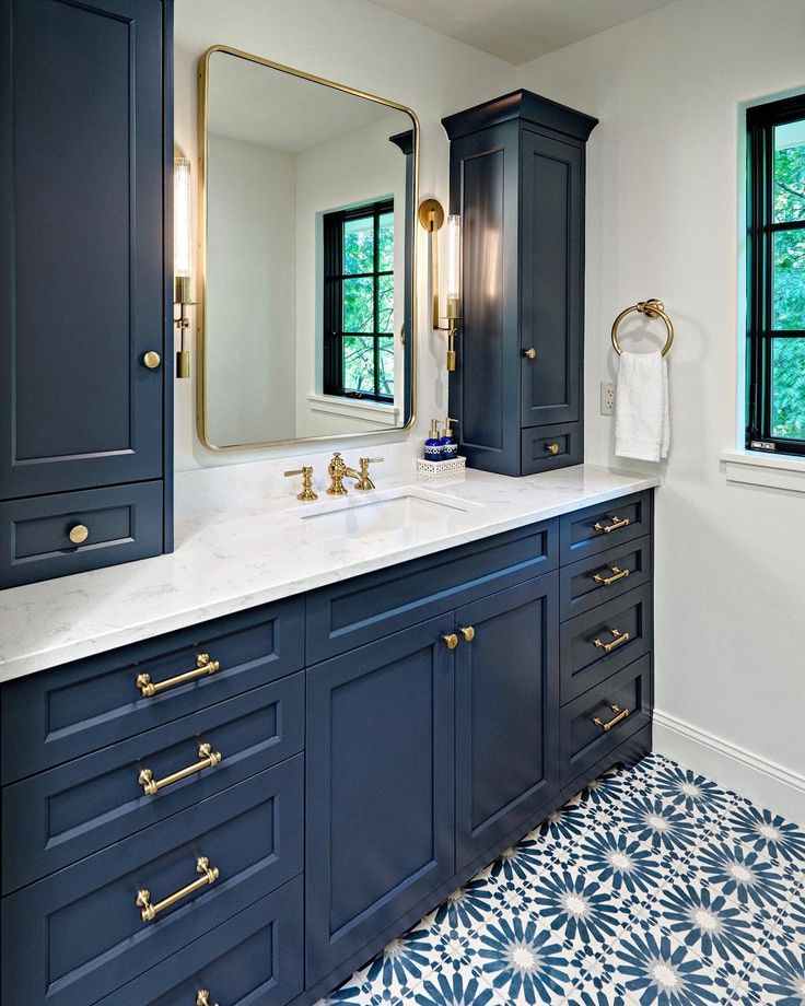 A navy cabinets with gold fixture and mirror on the wall
