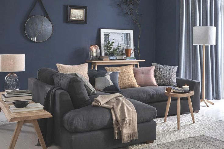 A blue living room with grey sofa with beige cushion and wooden table