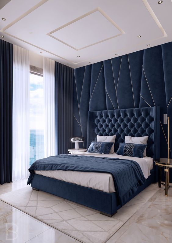 A bedroom with navy headboard wall and wooden floor and rug on it