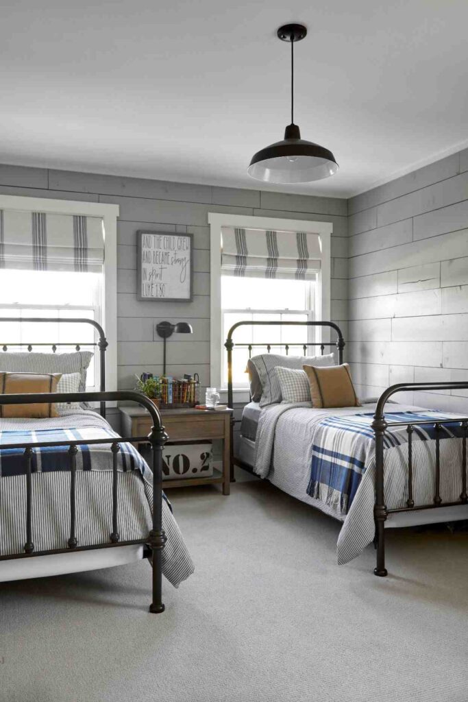 A grey bedroom with iron framed bed and windows 