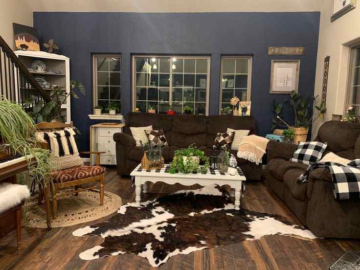 A navy and grey living room with plant and wooden floor and brown sofa with white table