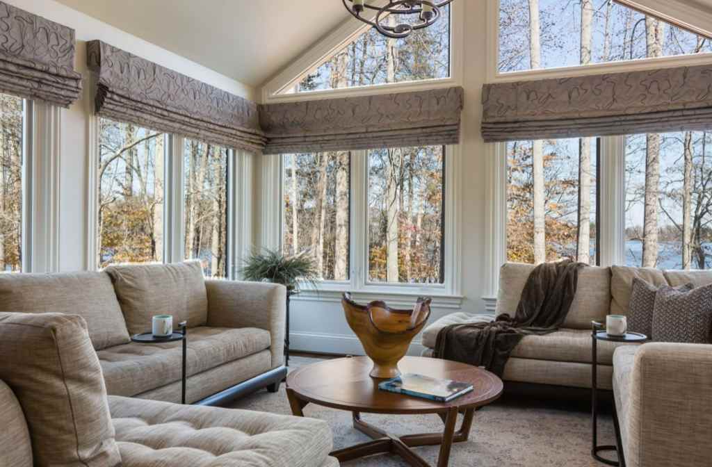 A roman shades in sunroom and wooden floor and table with sofa 