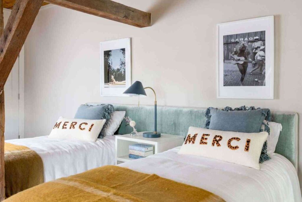 A bedroom with twin bed and shared lamp on the  nightstand 
