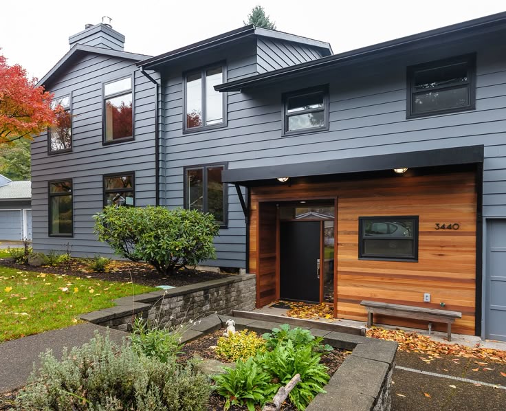 A slate blue house with black trim windows and wooden door