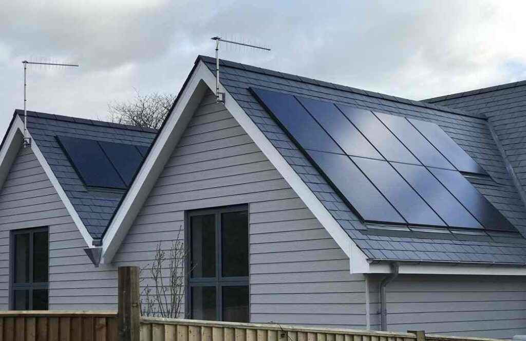 A grey house with black windows and solar panels 