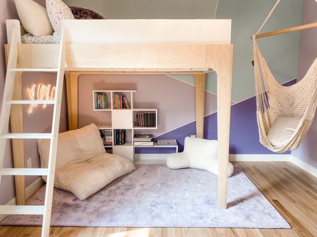 A wooden loft bed with stairs and sitting area and white rug on the wooden floor 